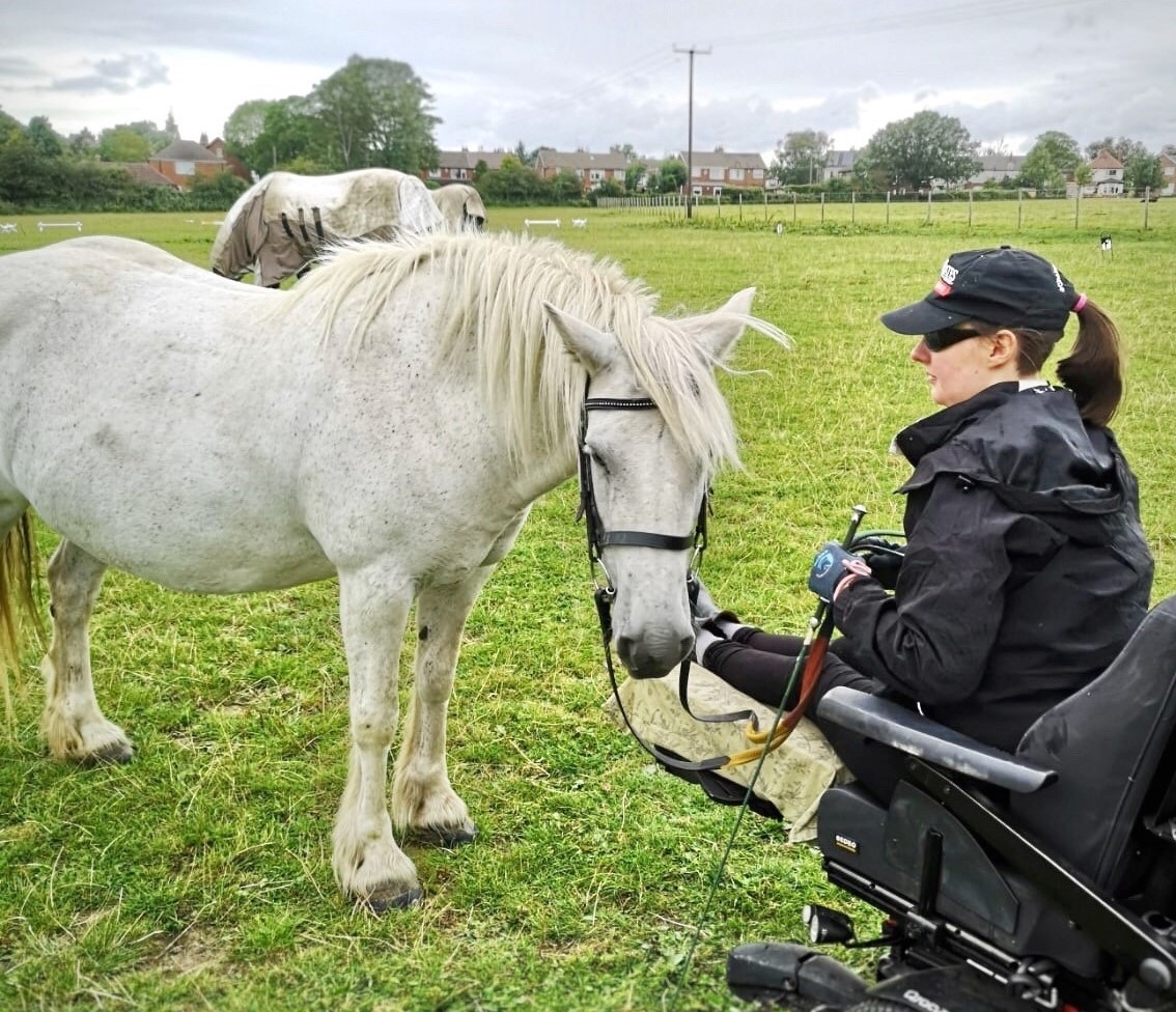 Groundwork. A girl sat in a Quickie Q700 Sedeo Pro wheelchair, holding the reins of a grey fell pony.